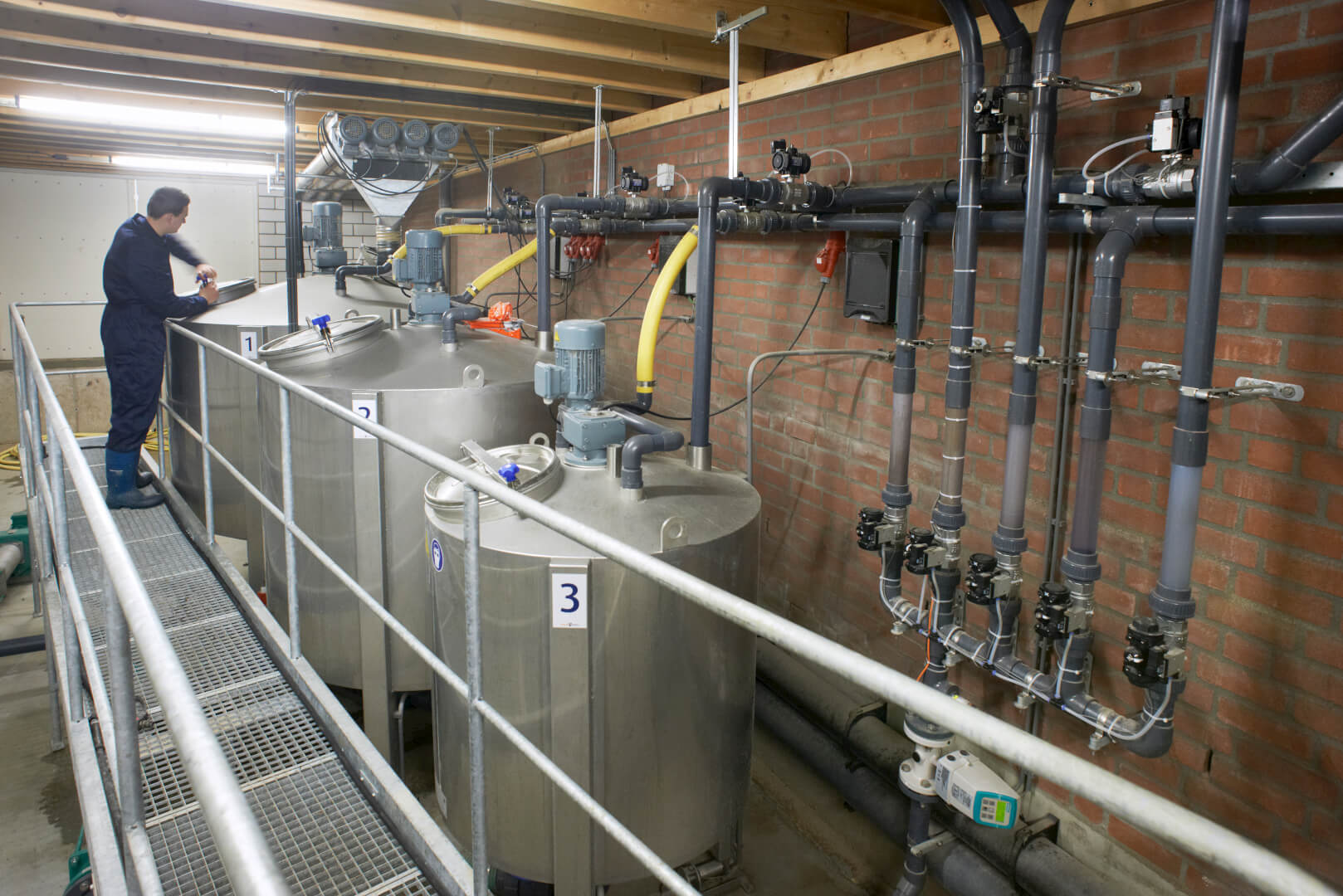 De voerkeuken met de restloze brijvoerinstallatie met drie rvs-tanks. De voerleidingen worden gespoeld met water.