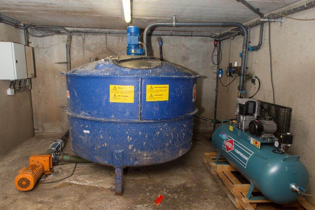 Bij de stal van de dragende en guste zeugen staat een tussenopslag van waaruit deze zeugen hun voer krijgen.